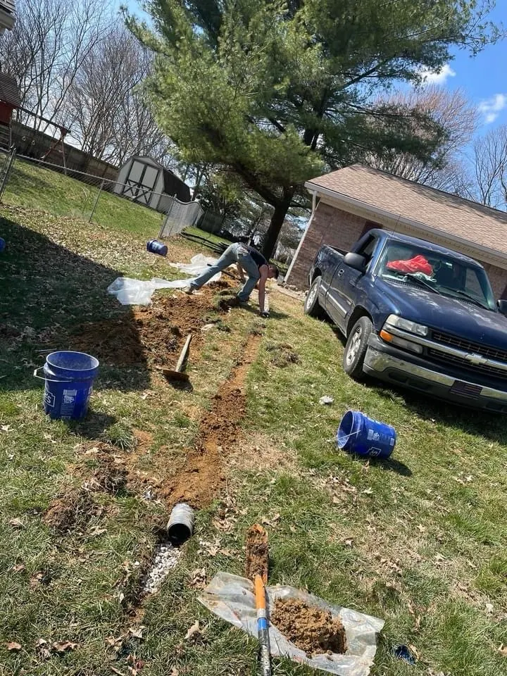 Yard drainage installation with equipment and materials staged outside
